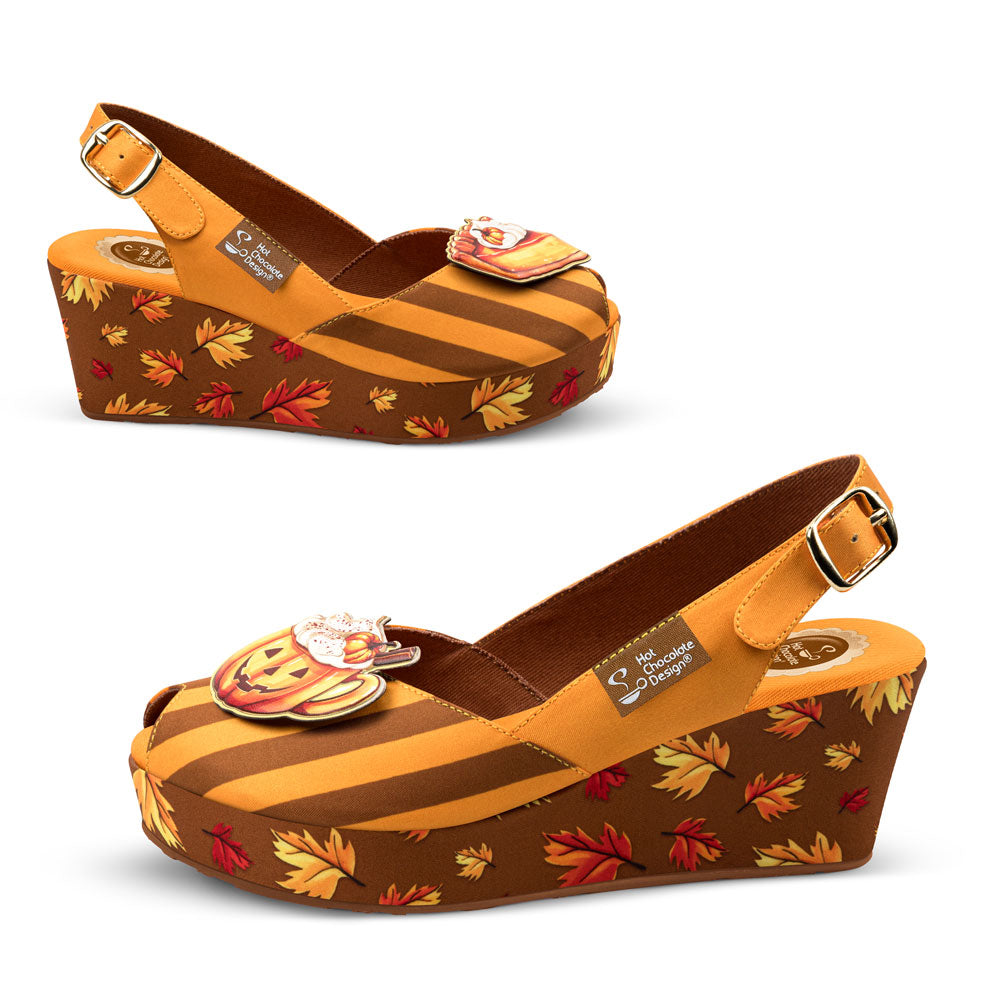 Wedge shoes with autumn leaf pattern and pumpkin charm on a white background