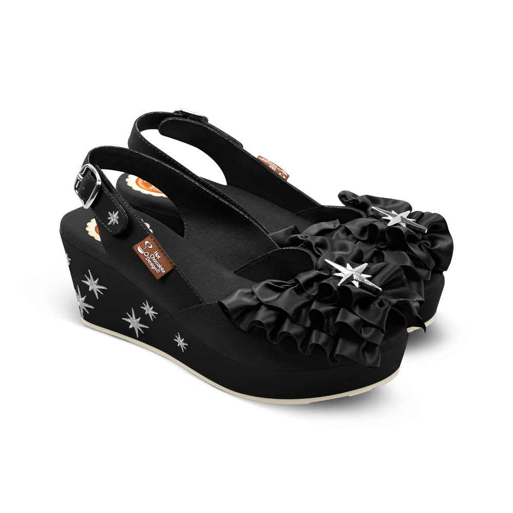 Black wedge sandals with ruffles and star designs on a white background