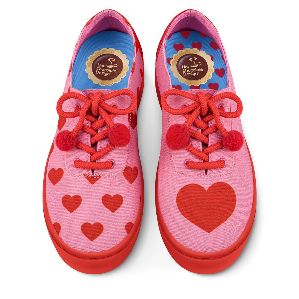 Pink shoes with red hearts and red laces on a white background