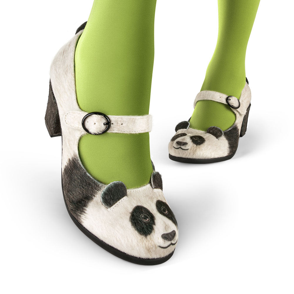 Panda-themed shoes worn with green tights on a white background
