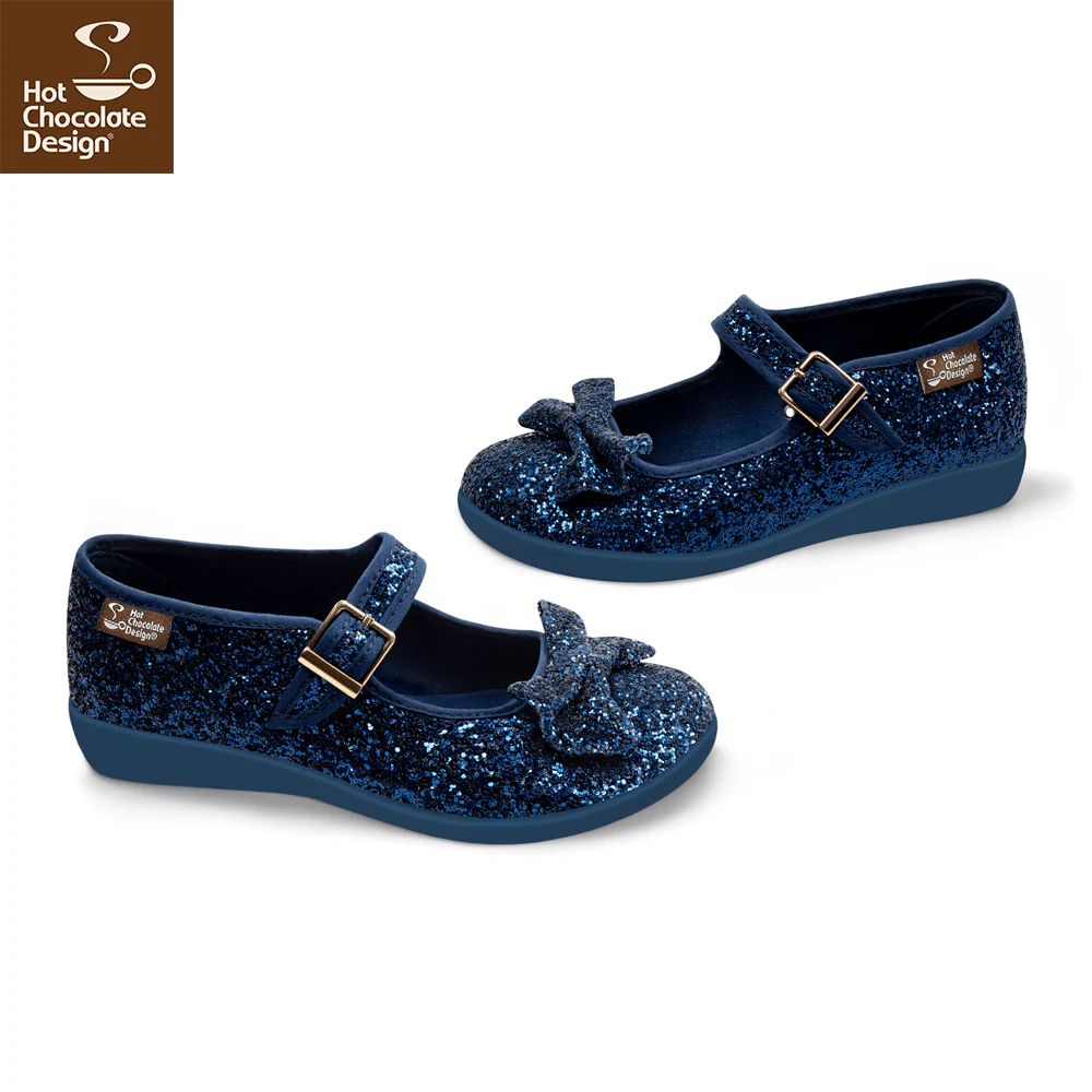 Pair of blue glittery shoes with bow details on a white background, featuring Hot Chocolate Design logo.
