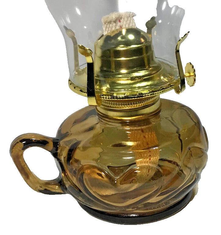 Vintage-style oil lamp with a gold metal top and clear glass base on a white background