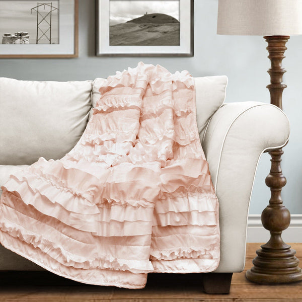 Pink ruffled blanket draped over a white sofa in a living room setting.