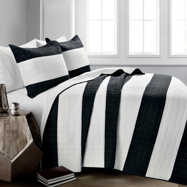 Black and white striped bedding set on a bed in a bedroom setting.