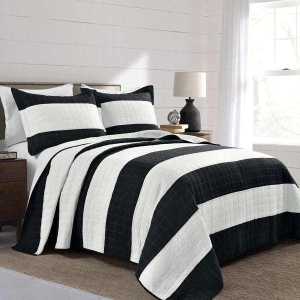 Black and white striped quilt on a bed in a bedroom setting.