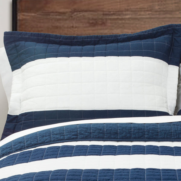 Navy and white striped quilt on a bed with wooden headboard