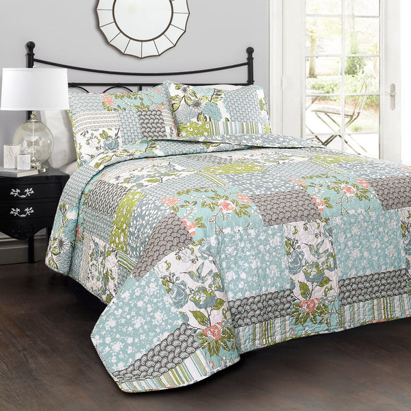 Bed with floral patchwork quilt and matching pillows in a bedroom setting.