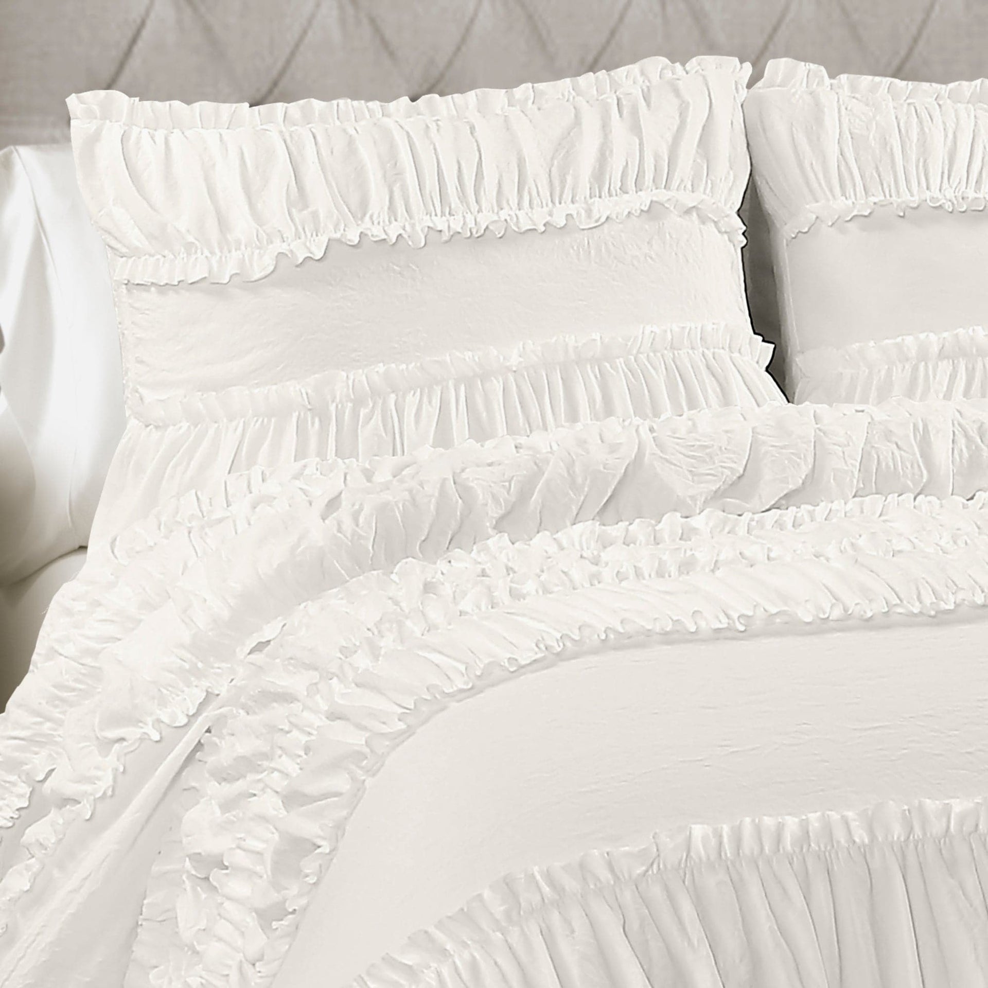 White ruffled pillows on a bed with a neutral background