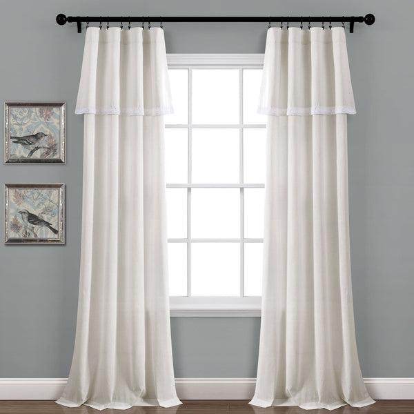 White curtains hanging in front of a window with gray walls and framed pictures.