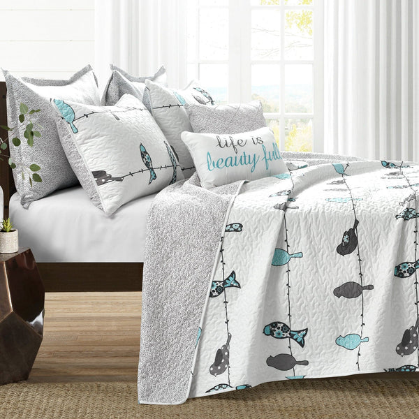 Bed with decorative pillows and a quilt featuring fish patterns in a bedroom setting.