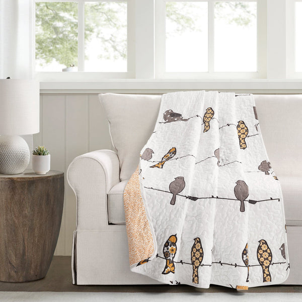 Decorative blanket with bird pattern draped over a chair in a room with a window.