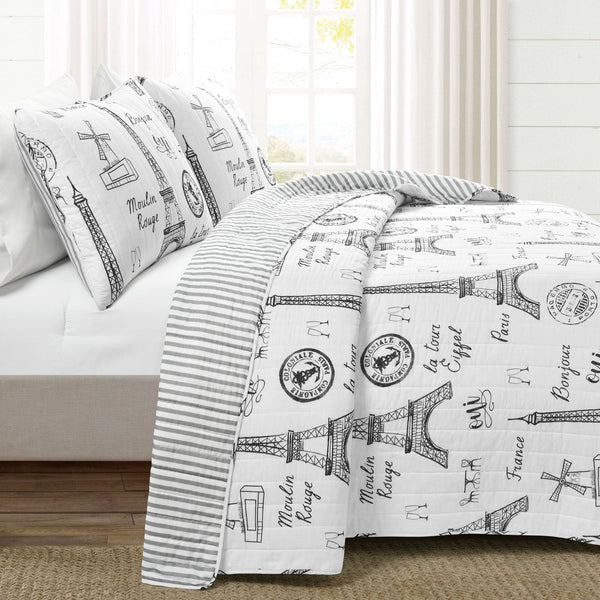 Bed with Paris-themed bedding featuring Eiffel Tower and French text.