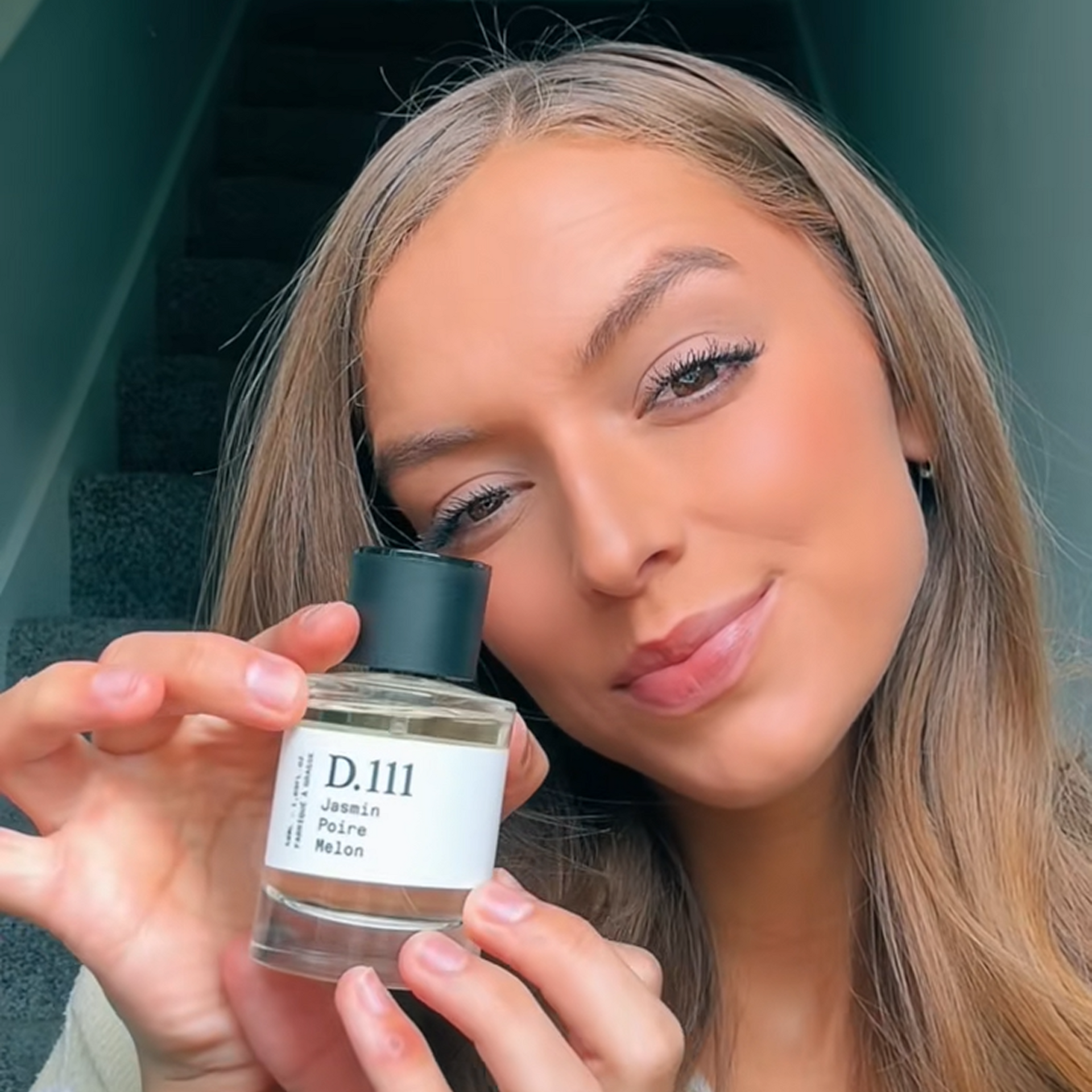 Woman holding a perfume bottle with a blurred background