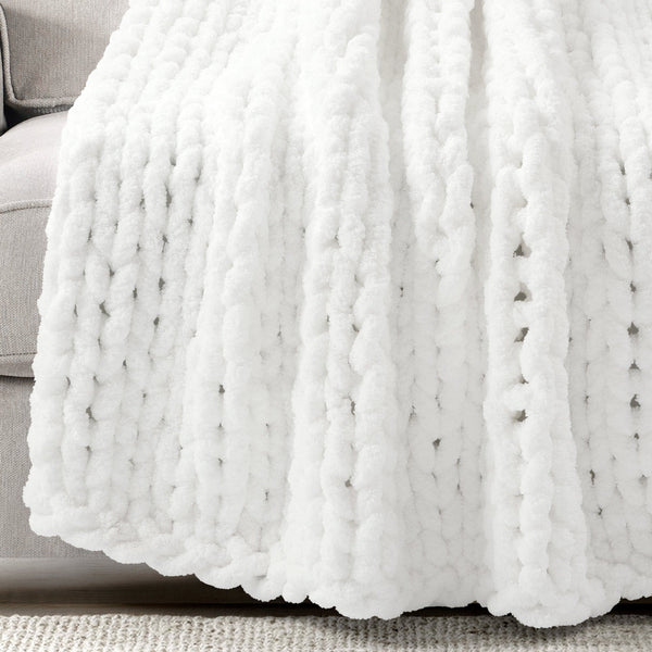 White chunky knit blanket draped over a gray sofa