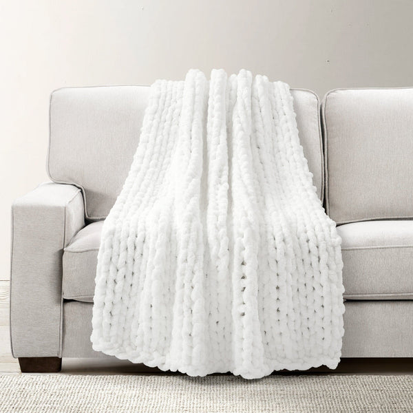 White textured blanket draped over a gray sofa on a light gray background