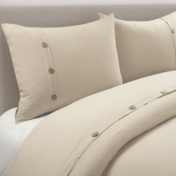 Beige bedding set with button details on a bed