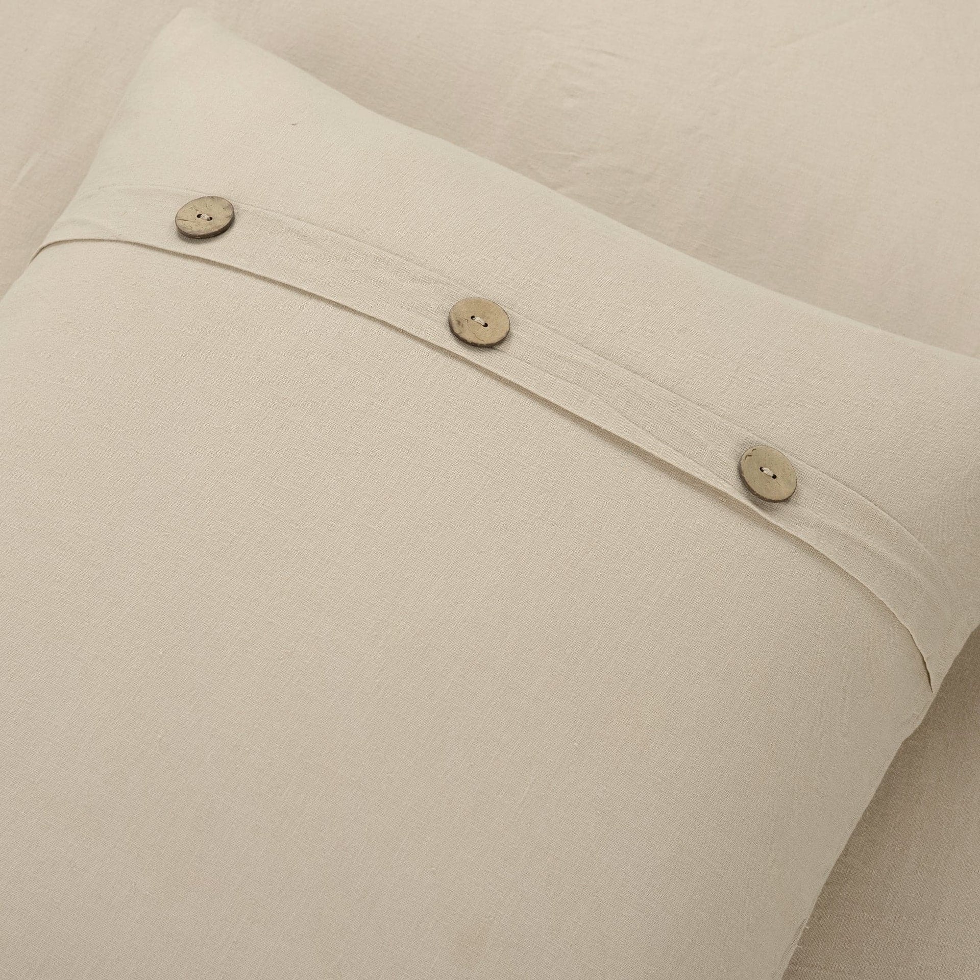 Close-up of beige fabric with buttons on a neutral background