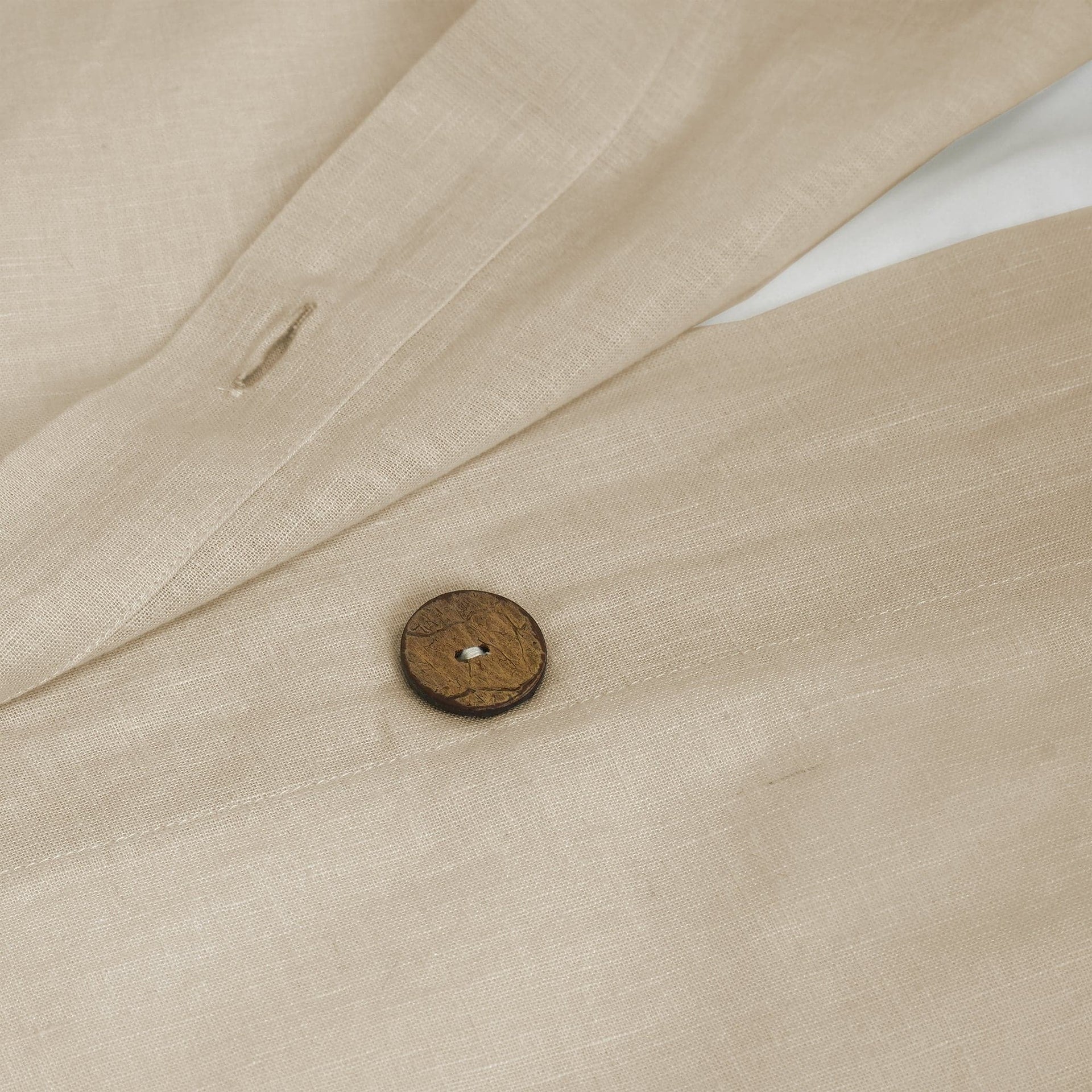Close-up of beige fabric with a wooden button