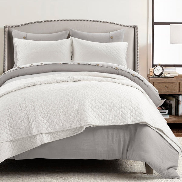 Neatly made bed with white bedding and pillows in a bedroom setting.