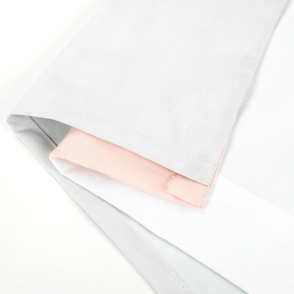 Close-up of a white towel with a pink bar of soap on a white background