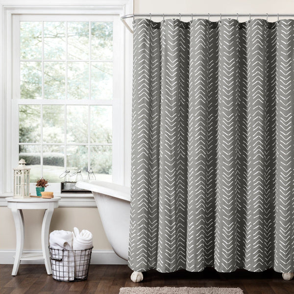 Bathroom with a gray and white chevron patterned shower curtain, bathtub, and window.