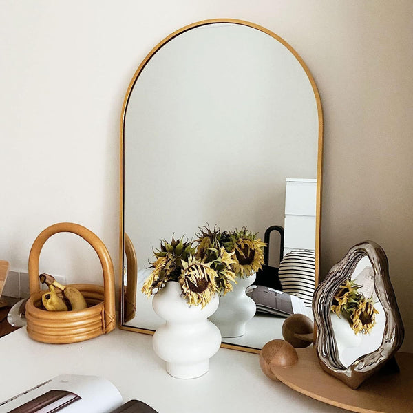 24x36 Inch Gold Metal Framed Arched Mirror styled on a desk with vases and dried flowers, enhancing home decor aesthetics.
