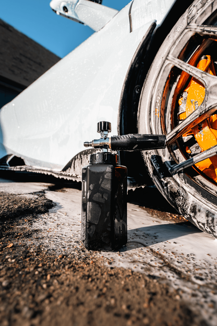 Black tire inflator next to a motorcycle wheel on a textured surface with a blue sky.