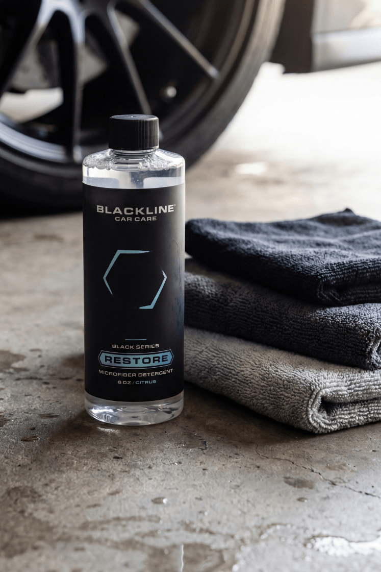 Blackline car care product bottle with towels on a concrete surface