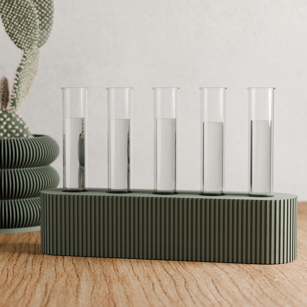 Decorative table piece with glass cylinders on a ribbed base, placed on a wooden surface.