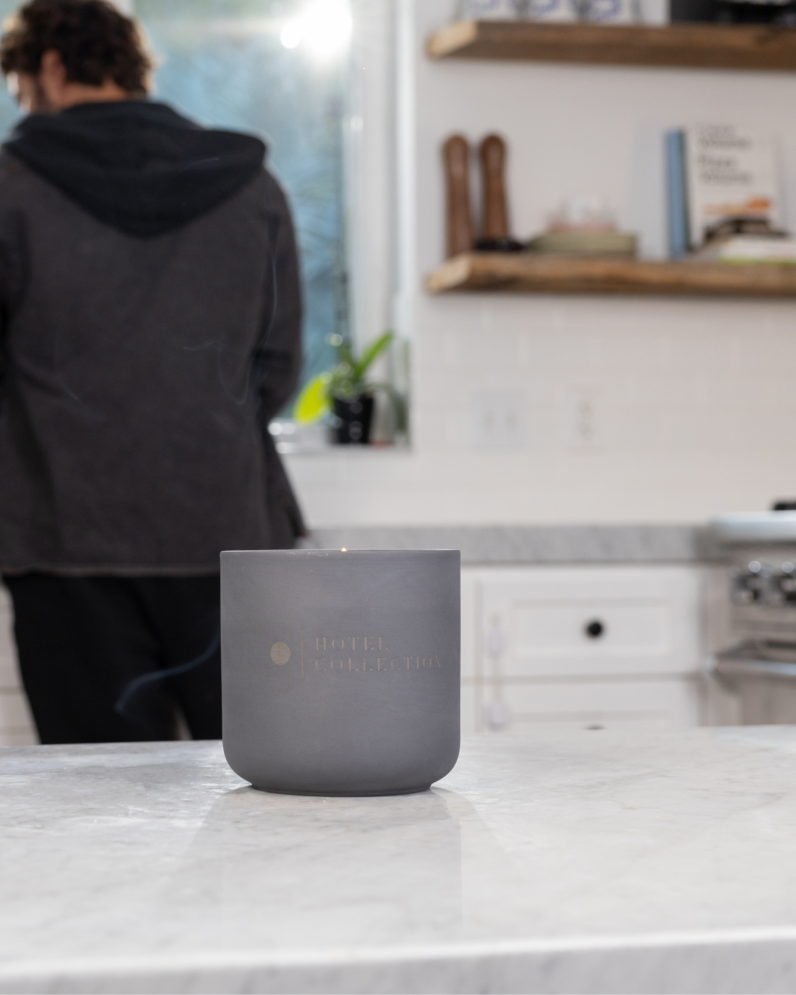Gray candle on a kitchen counter with a person in the background