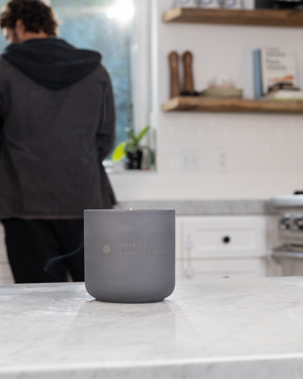 Gray candle on a kitchen counter with a person in the background