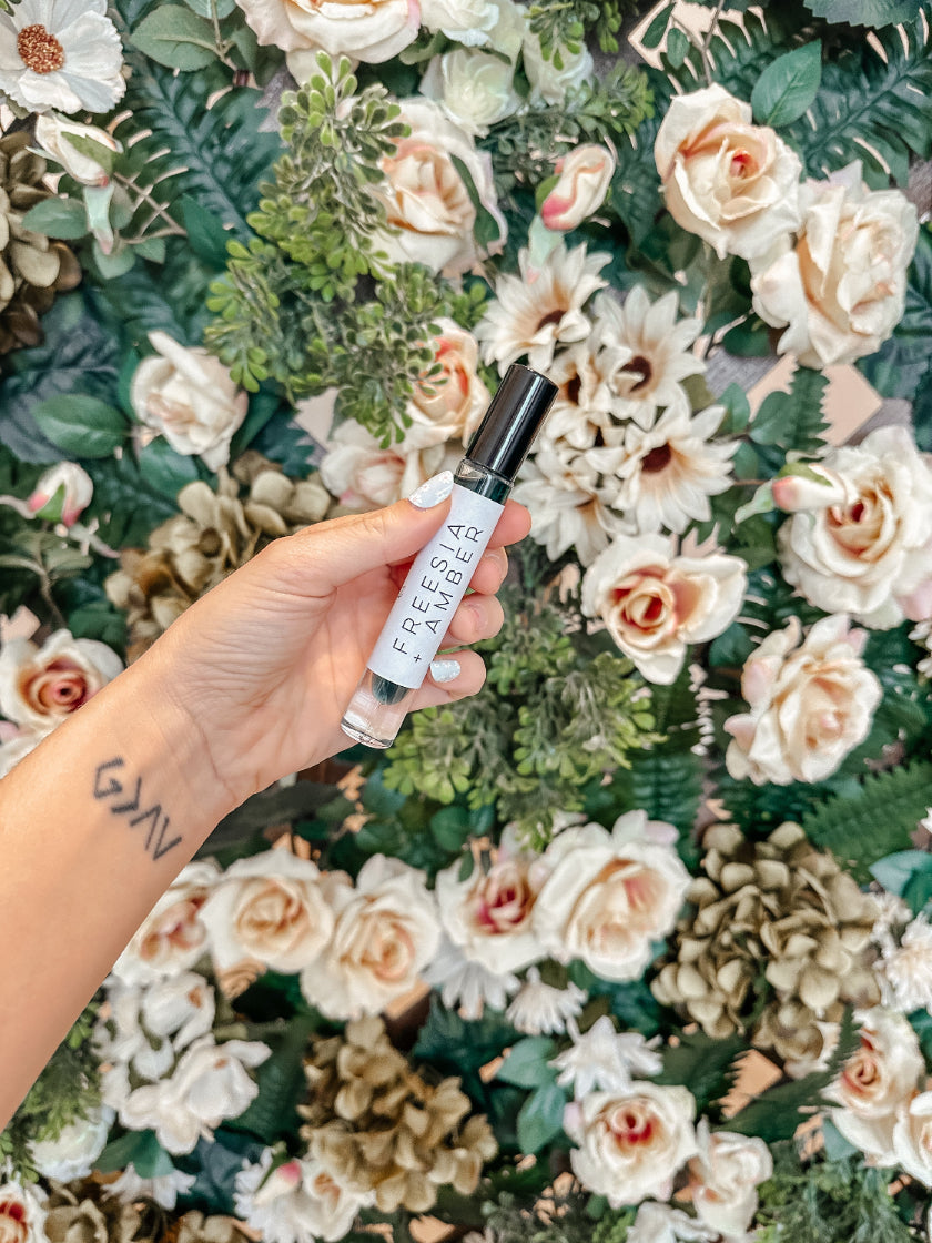 Hand holding a Freckle & Fair product against a floral background