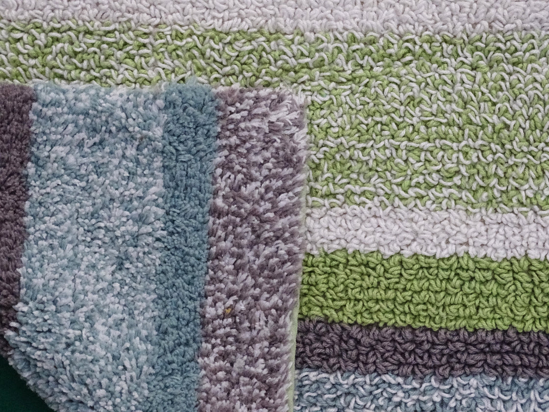 Close-up of textured bath mats with green, purple, and blue stripes.
