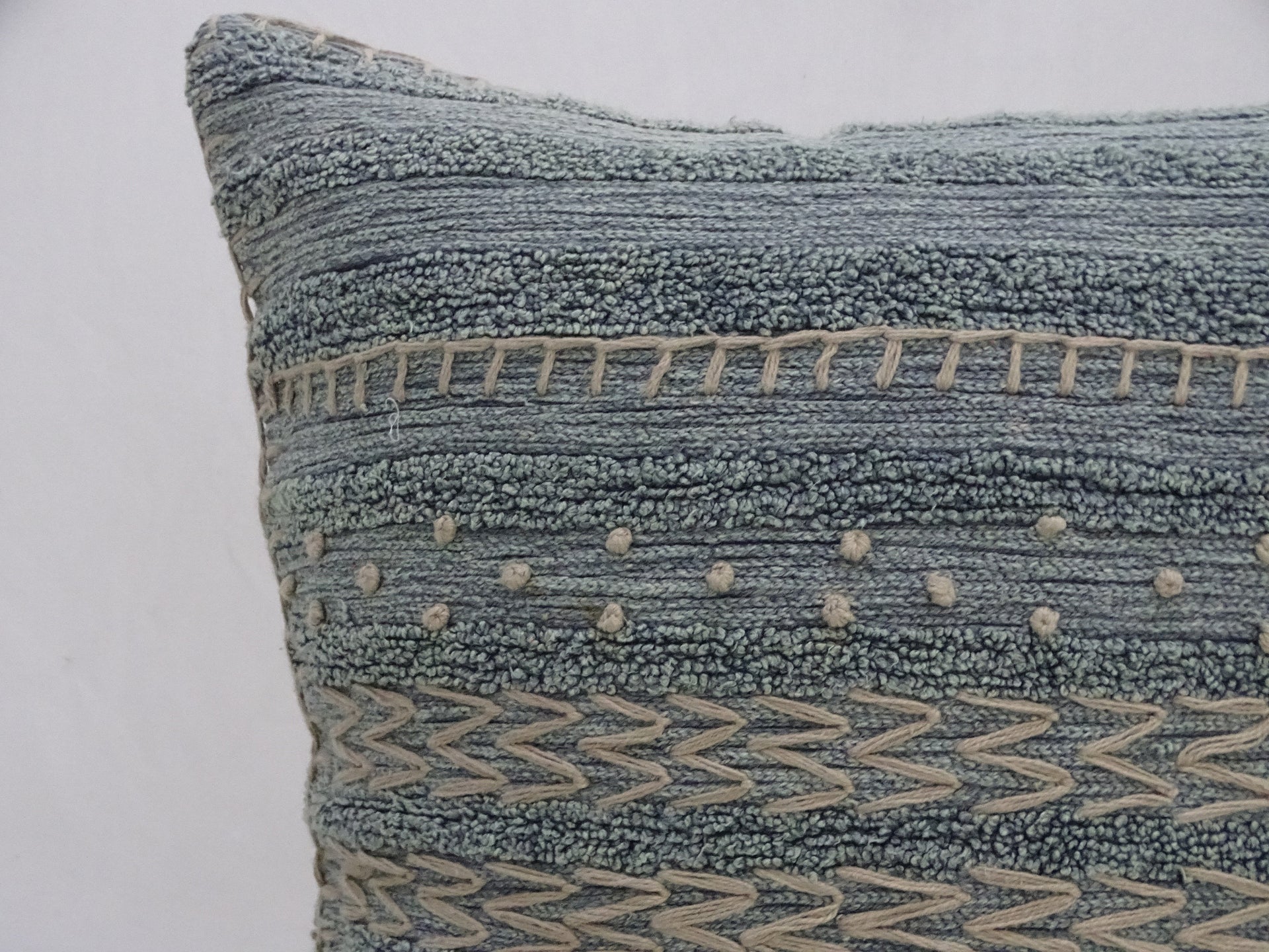 Textured blue pillow with geometric patterns on a white background