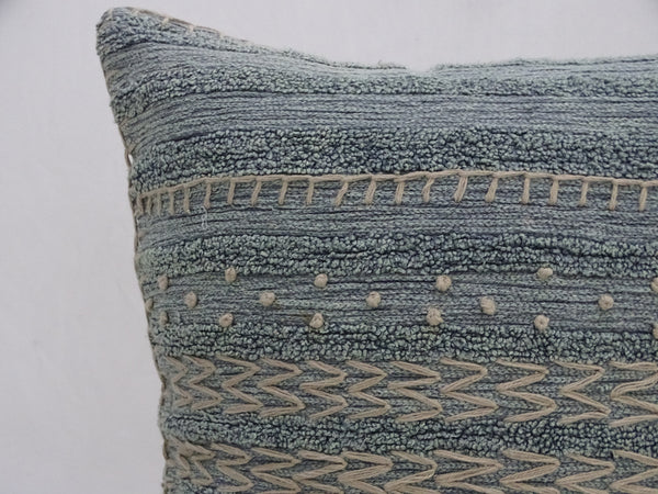 Textured blue pillow with geometric patterns on a white background