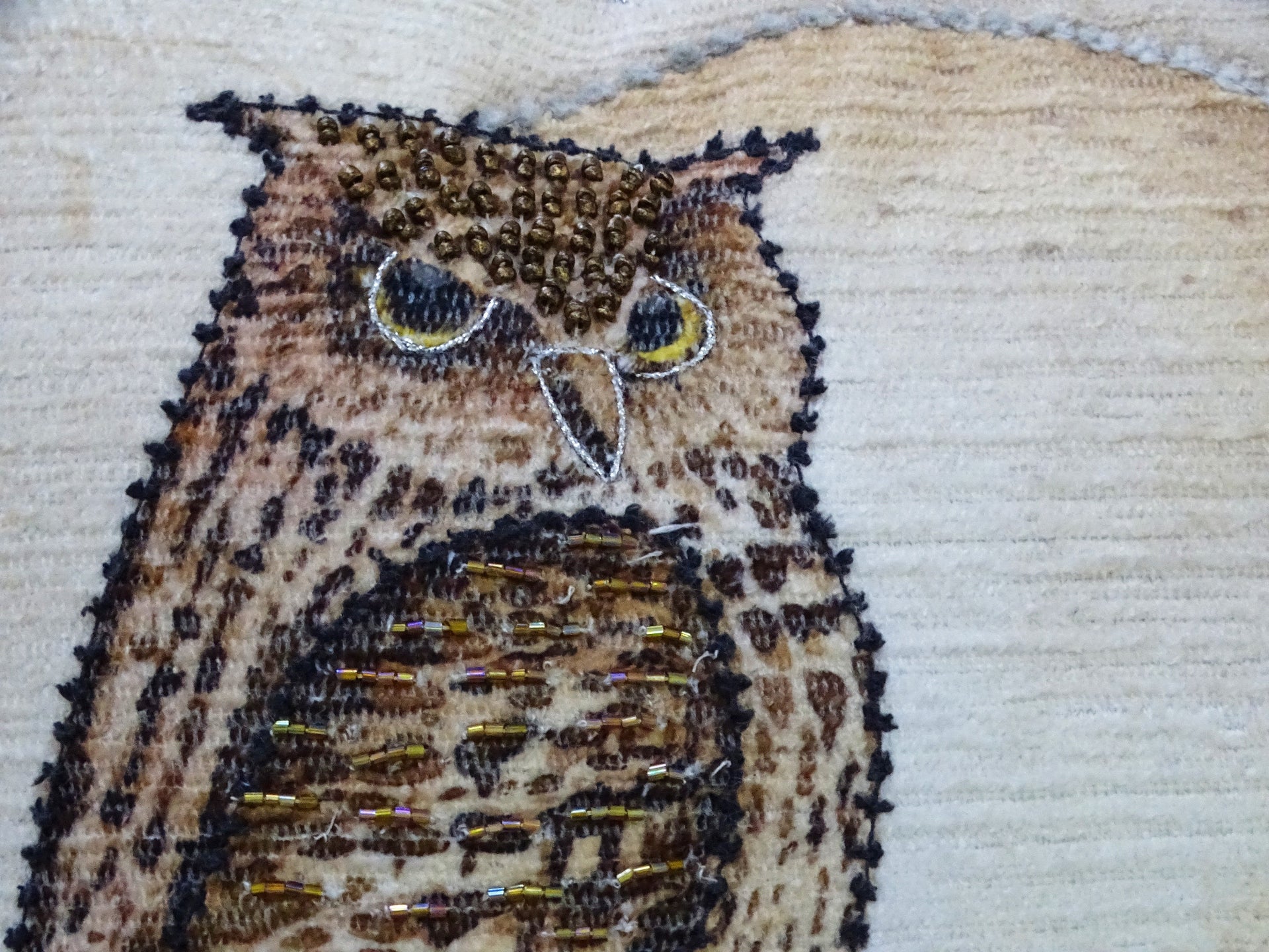 Embroidered owl design on fabric with a neutral background
