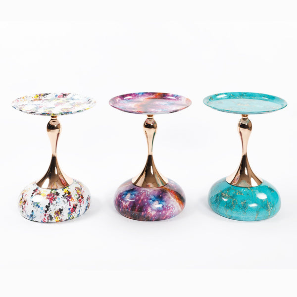 Three variations of Mermaid Tail End Coffee Table Round Side by Buddify, featuring galaxy, turquoise, and abstract paint designs with gold stems.