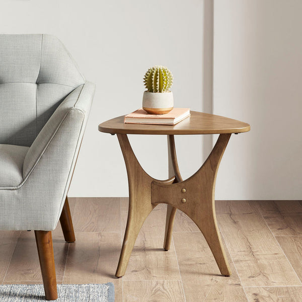 Triangle Wood Side Table placed beside a gray armchair in a modern living room, ideal for accent furniture styling.
