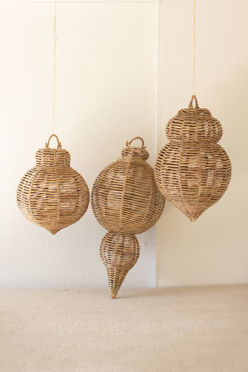 Three woven rattan ornaments hanging against a plain wall.