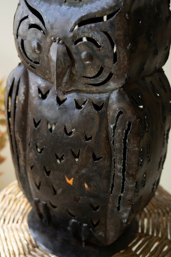Decorative owl lantern with cut-out design on a woven surface