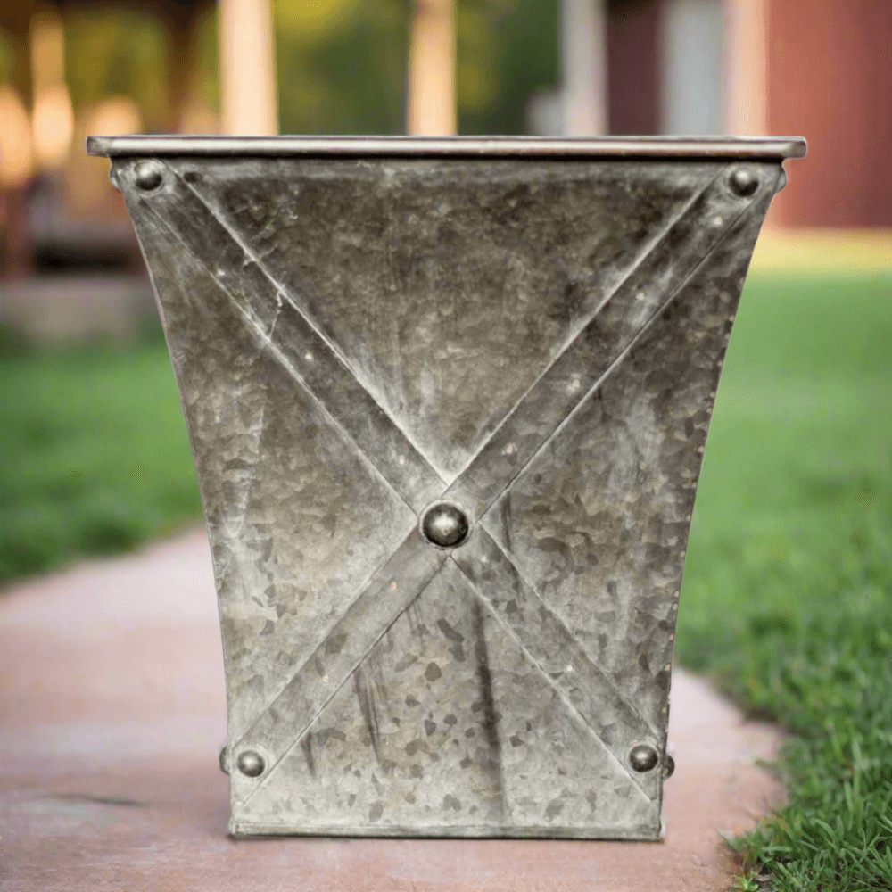 Metal planter with X-shaped design on a pathway outdoors
