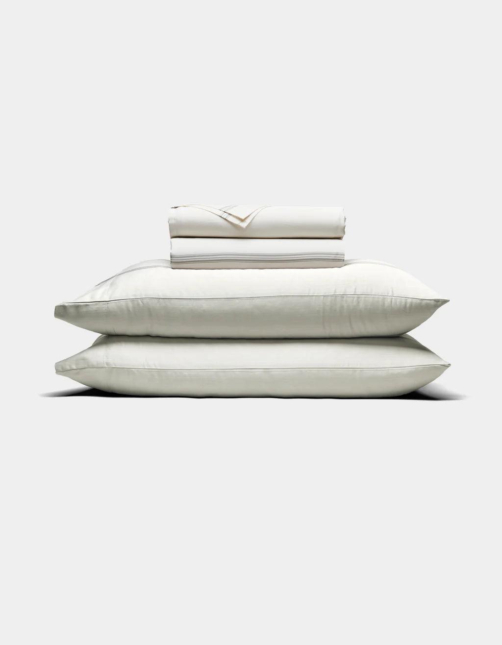 Baja Stripe in Laurel - Stack of white pillows and a folded sheet on a light gray background