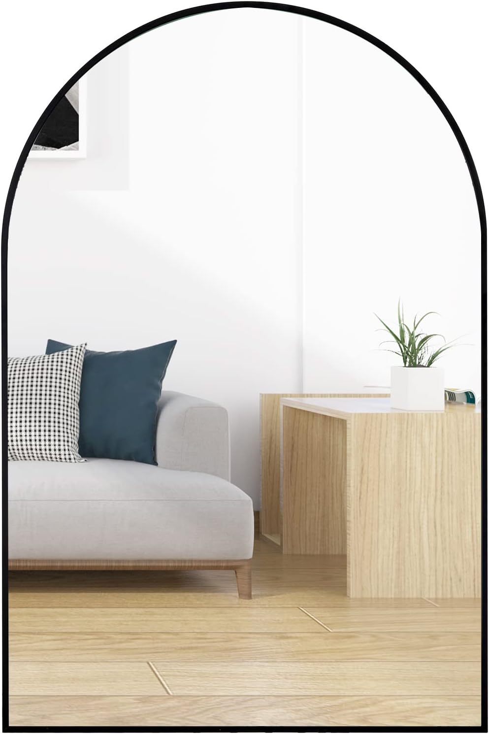 24x36 Inch Black Metal Framed Arched Wall Mirror mounted above a light wood console in a modern living room with a gray sofa and accent pillows.