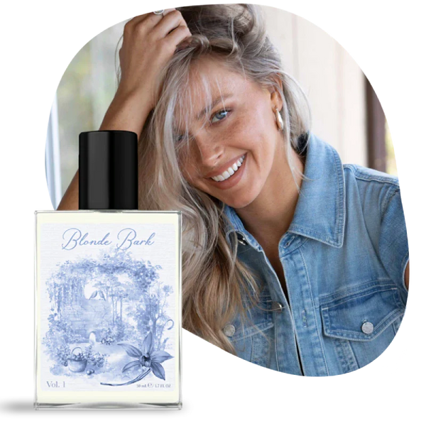 Woman with blonde hair and denim jacket next to a bottle of 'Blonde Bark' perfume.