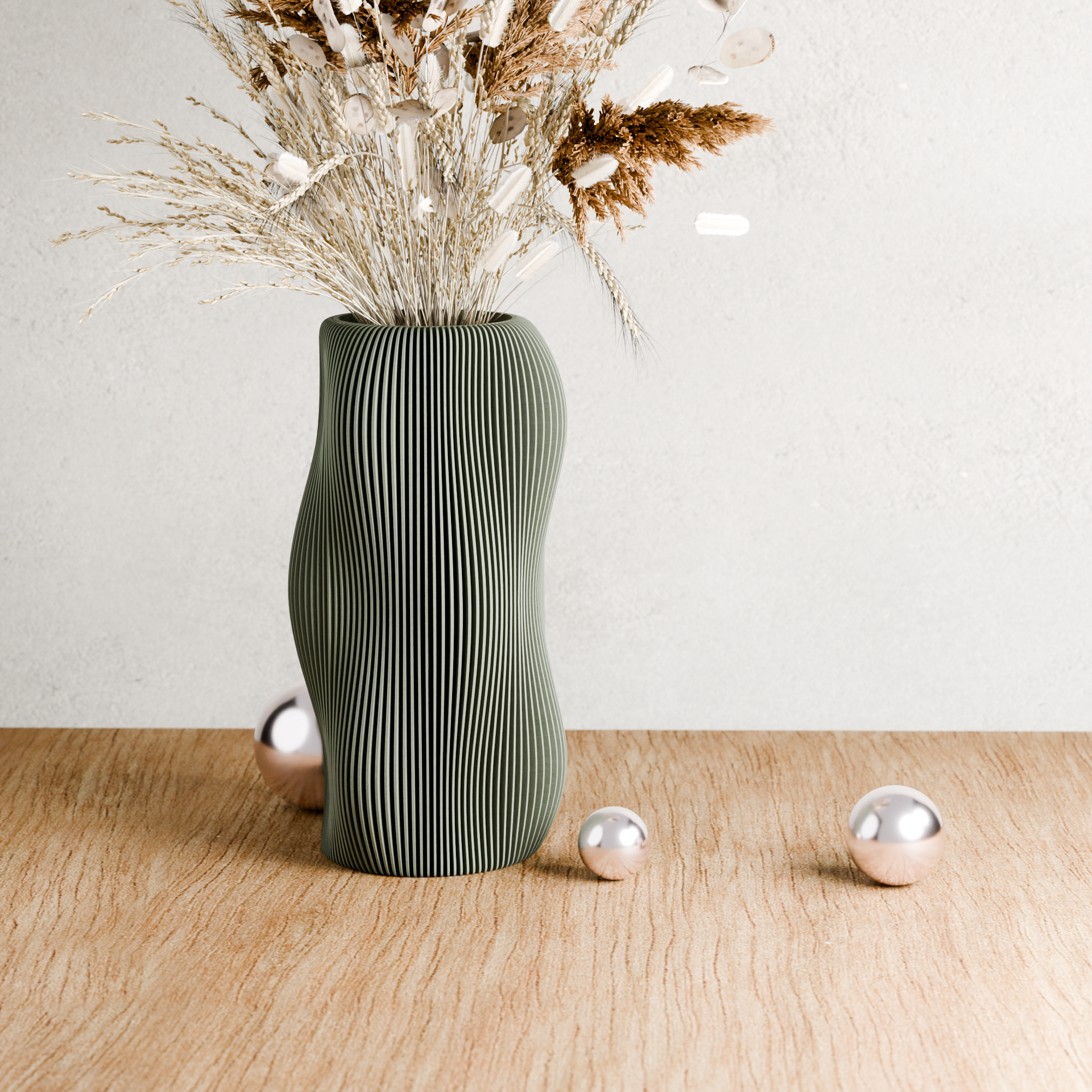 Green textured vase with dried flowers on a wooden surface