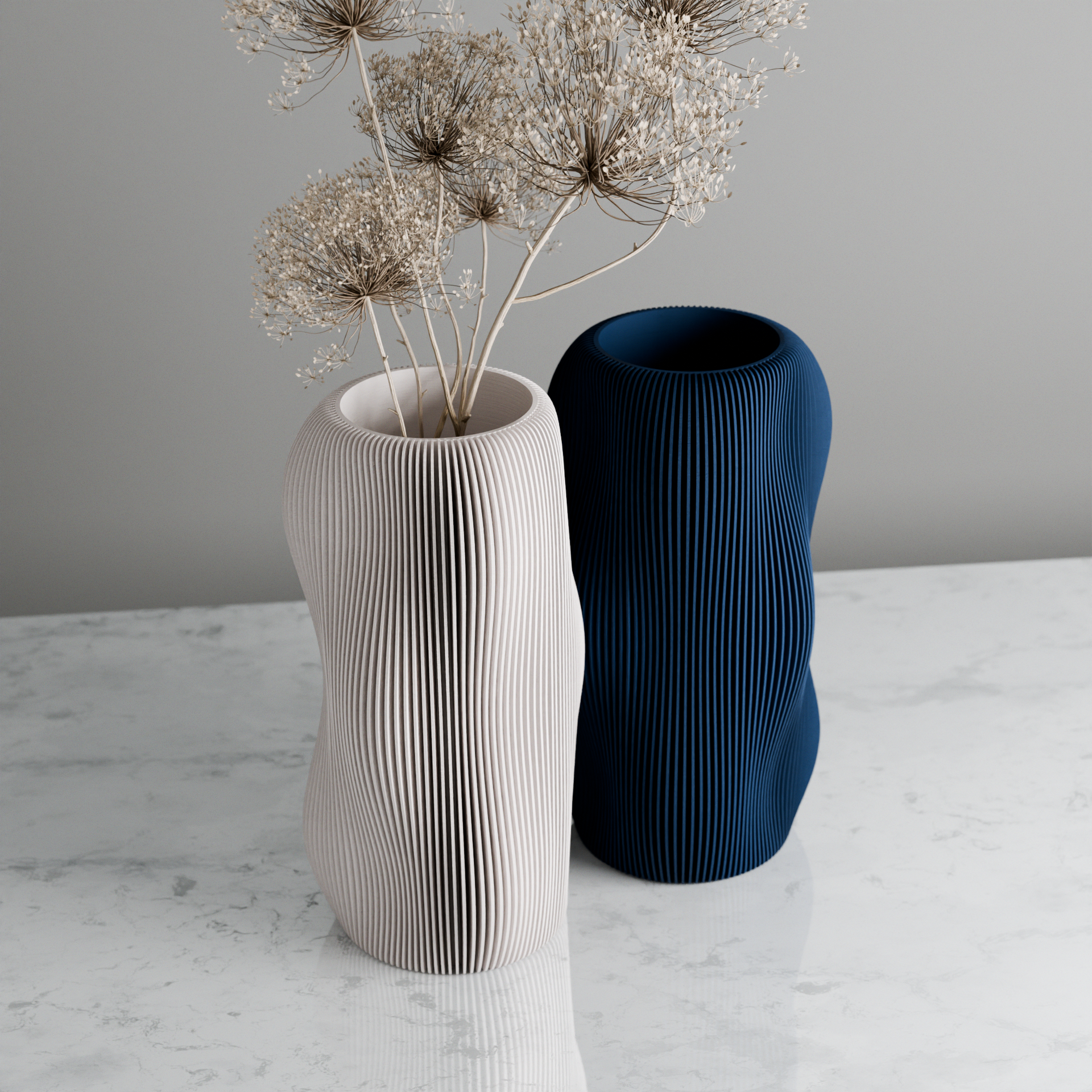 Two textured vases, one white and one blue, on a marble surface with a gray background.