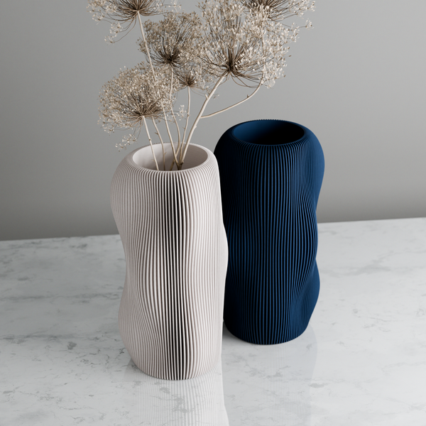 Two textured vases, one white and one blue, on a marble surface with a gray background.