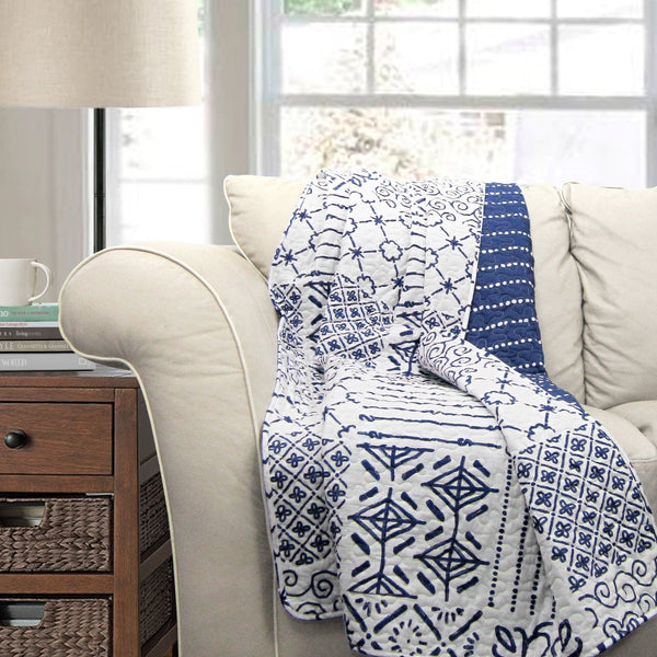 Beige sofa with a blue and white patterned throw blanket in a living room setting.