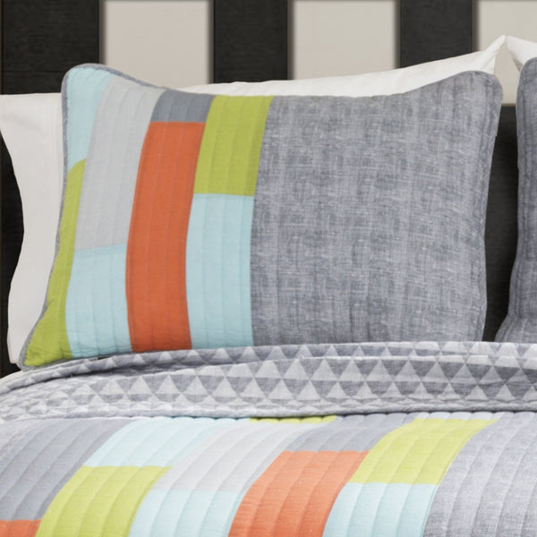 Colorful striped pillow and bedding set on a bed with a dark headboard.