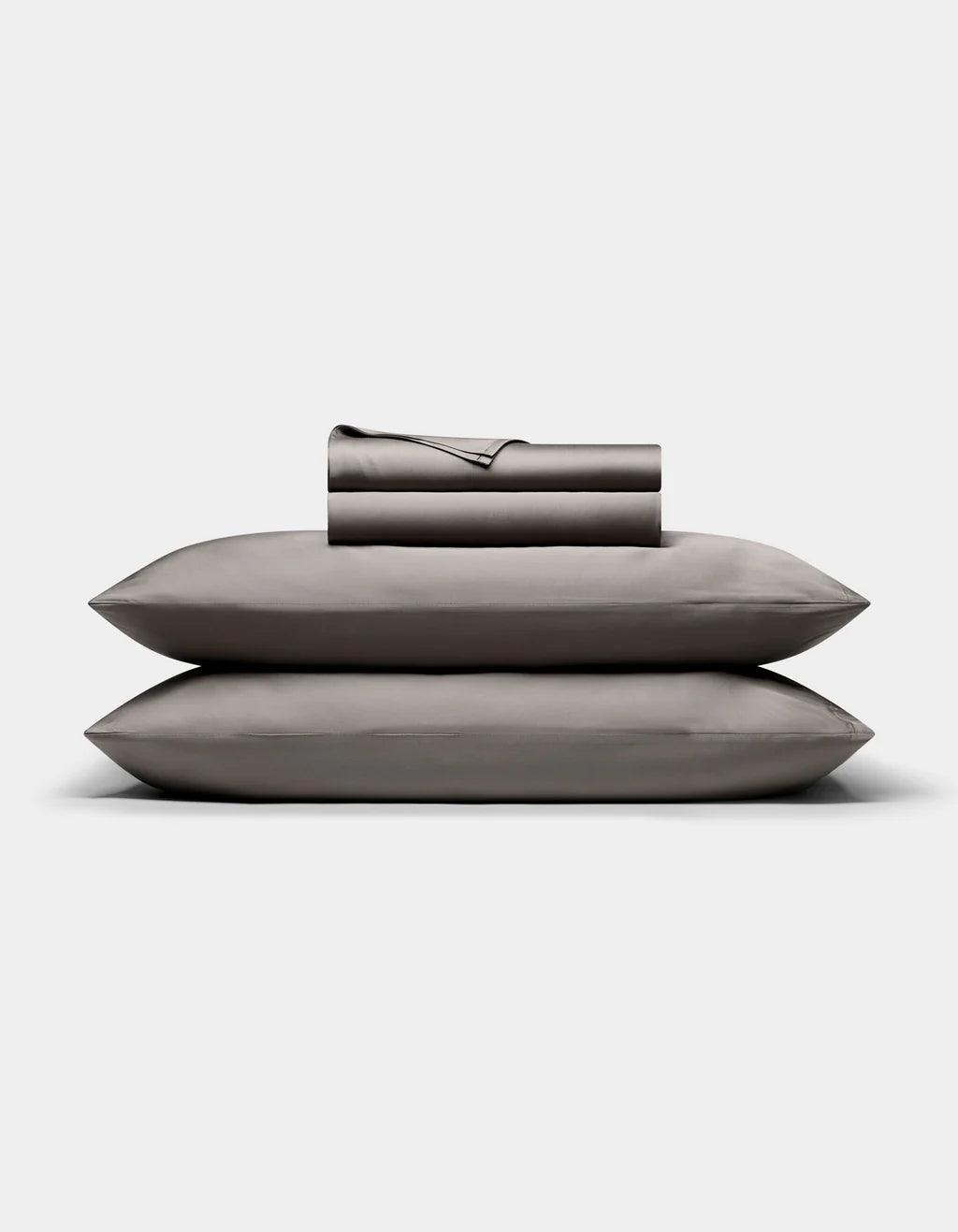 Set of Charcoal pillows and a folded blanket on a light gray background